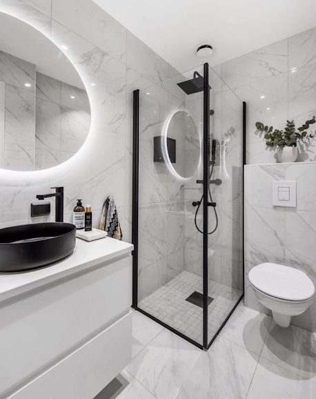 Compact marble effect en-suite with black framed corner shower enclosure